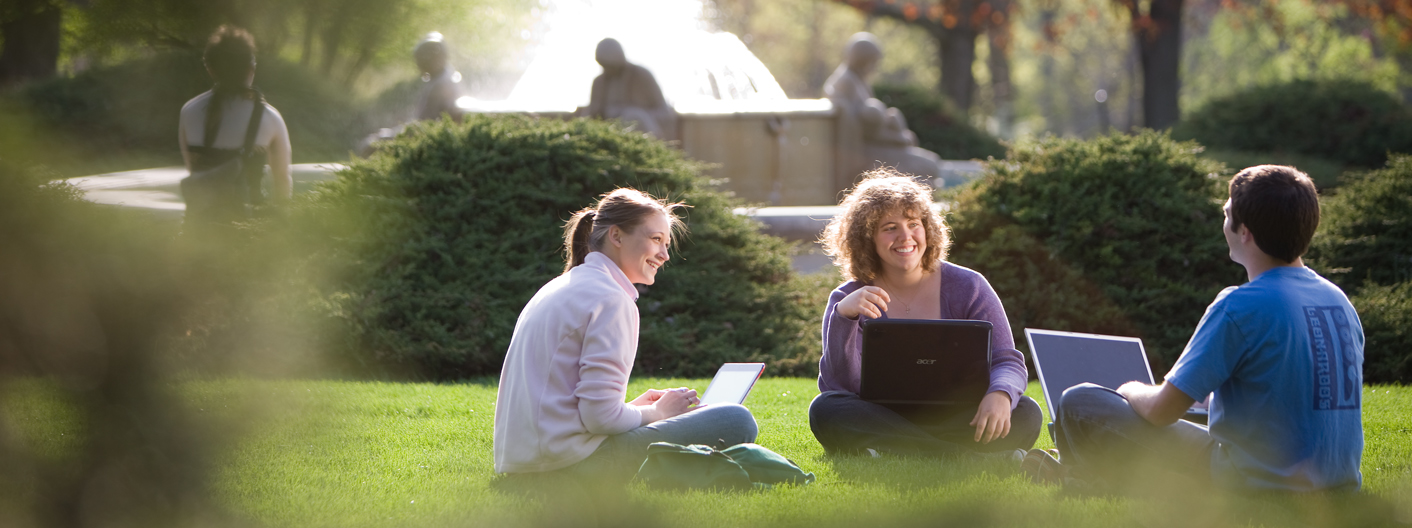 Three students sit outside by the Memorial Union fountain on the Iowa State campus