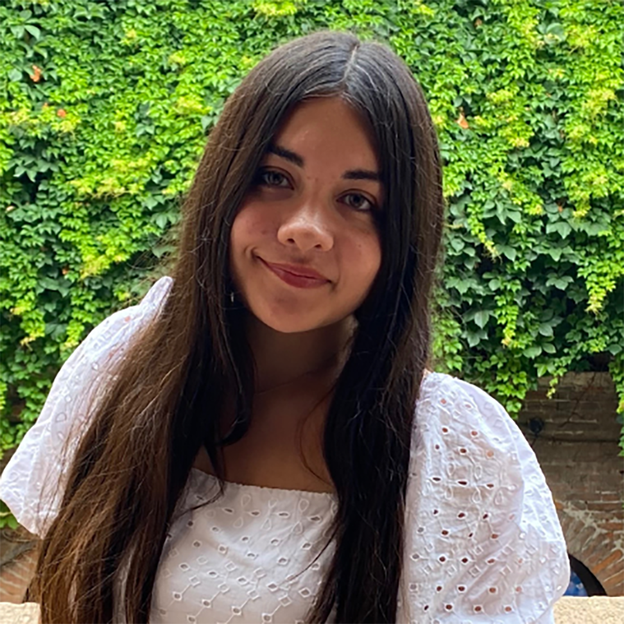 Jazmin Chavez outside near an ivy covered wall smiliong
