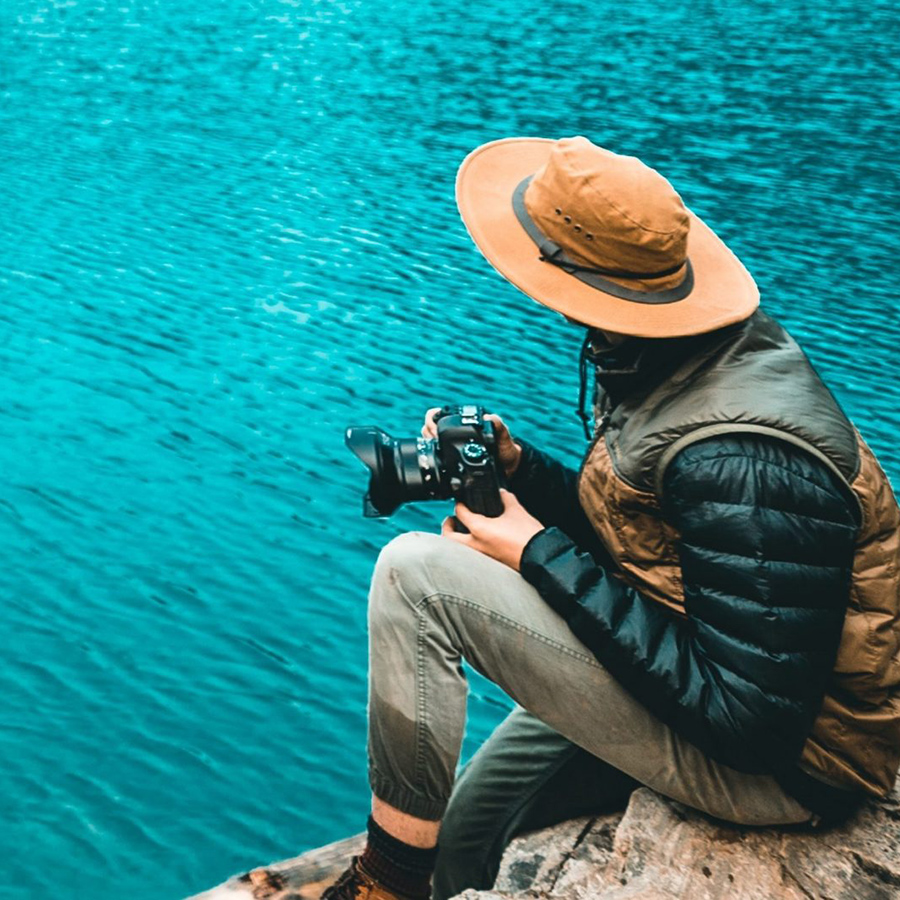 a photographer sits by a body of water with a camera