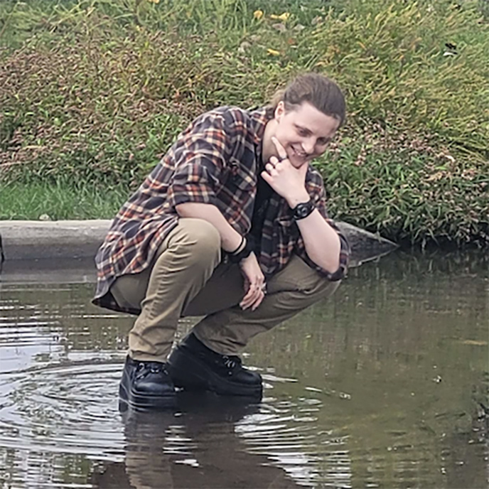 Atlas Kunkle outside crouching down in shallow water