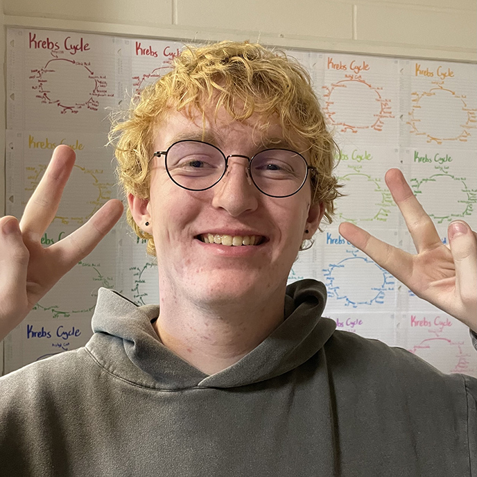 Ben Marshall smiling while holding up two fingers in each hand as peace signs