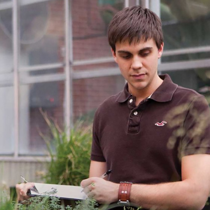 a CALS student takes notes on a clipboard in a greenhouse