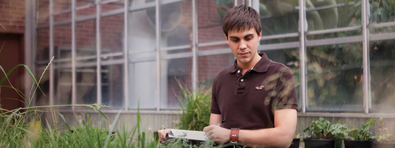 a CALS student takes notes on a clipboard in a greenhouse