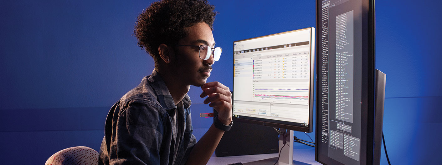 An engineering student looks over some code on a computer monitor