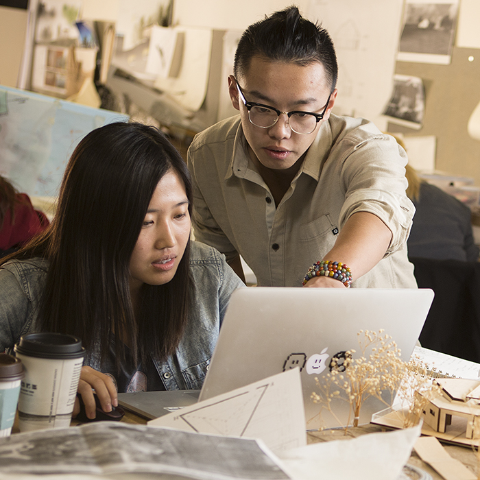 two design students work on a project together on a laptop