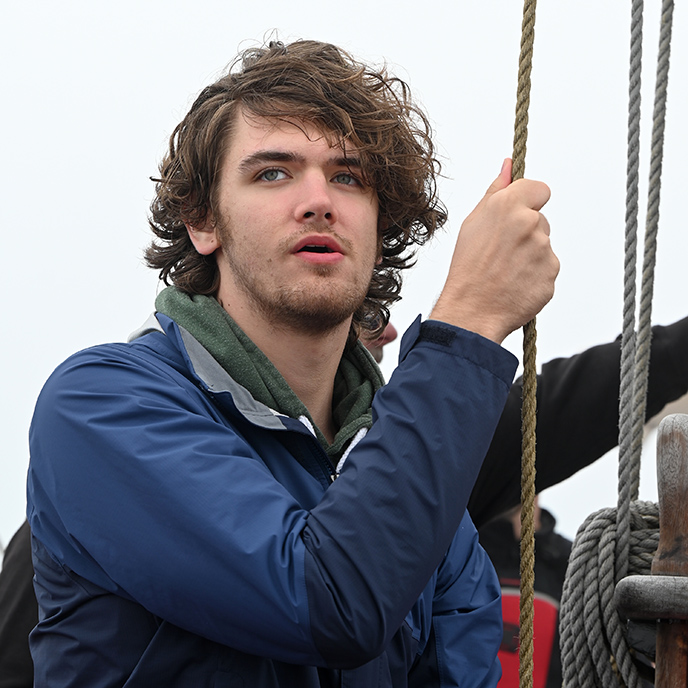 Logan Barleen outside holding a rope and looking into the distance