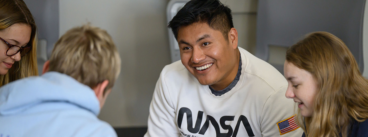 A smiling instructor leads a group of students in a small group discussion