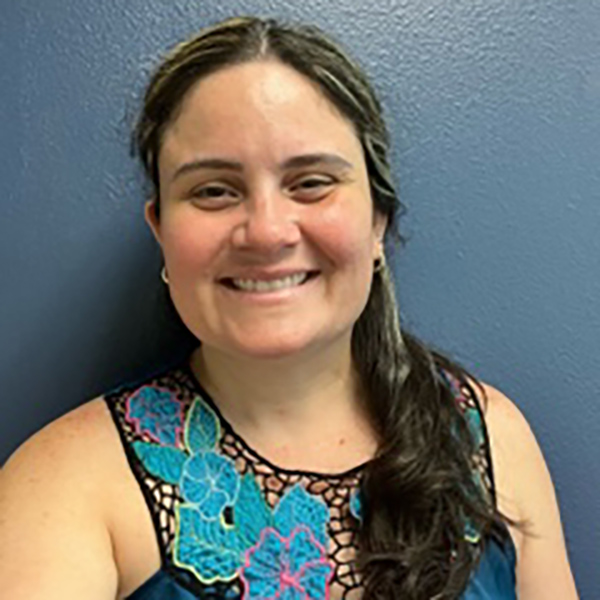 Arlenne Negron smiling against a pale blue wall