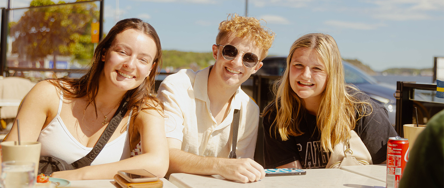 Three students sitting at a table and smiling while on a Study Abroad trip